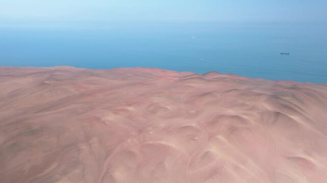 Aerial View of Ocean and Desert Coastline at Paracas National Reserve, Peru. This stunning aerial footage captures the breathtaking contrast between the deep blue Pacific Ocean and the arid desert 