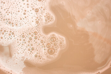Fototapeta premium White soap foam on beige background, abstract backdrop for product placement