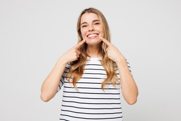 Young happy smiling Caucasian cheerful woman wear striped t-shirt casual clothes point index...