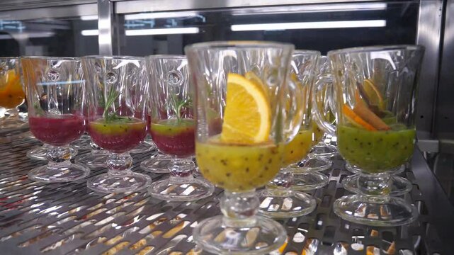 Punch preparations in mugs, standing in a row. Hot and healthy drinks. Orange, cherry, apple and other punches. Restaurant, buffet, hotel catering.