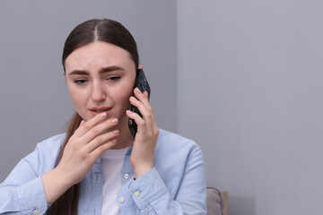 Stressed woman calling hotline for mental health help at home. Space for text
