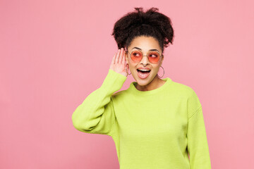 Young curious nosy woman of African American ethnicity wear green sweater casual clothes try to...