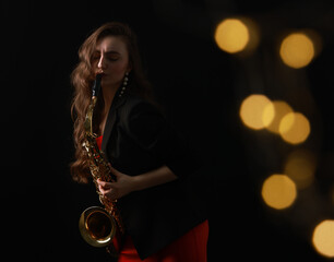 Professional musician playing saxophone on black background with blurred lights. Bokeh effect
