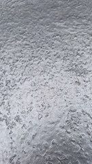 Close-up of a textured, silver metallic surface with a rough, industrial feel
