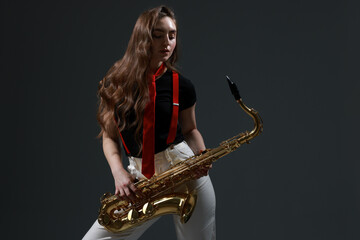 Professional musician with saxophone on grey background
