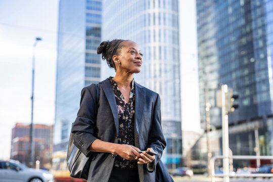Confident mature business woman using mobile phone in the city

