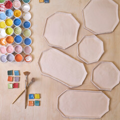 top view of handmade clay plates and glaze jars ready for painting