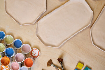 top view of handmade clay plates and glaze jars ready for painting