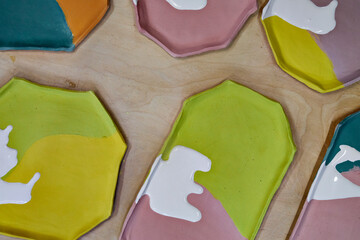 top view of handmade clay plates covered with colored glazes, ready for firing