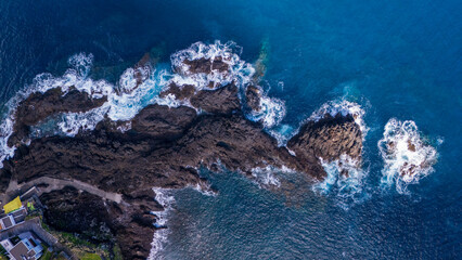 Coastal rock formations under vibrant waves at midday, showcasing nature's strength and beauty