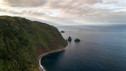 Stunning coastal cliffs and serene ocean embrace a tranquil shoreline at sunset