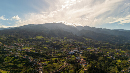 Majestic mountains embrace a serene valley in a vibrant countryside landscape at golden hour