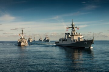 Obraz premium Naval vessels conduct coordinated exercises in calm waters under a clear blue sky