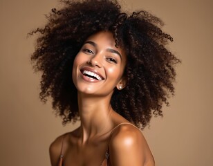 Studio portrait of a beautiful smiling woman with afro curls hairstyle. Attractive girl with perfect skin and white teeth smiles at camera. Brunette female, happy face. Beauty and fashion.