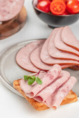 Delicious sandwich with sausage slices on white background