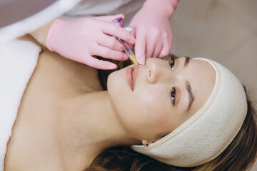Cosmetic professional applying dermal filler to patient's lips during aesthetic treatment at...