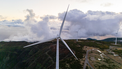 Captivating wind turbines gracefully spinning under a dramatic sky on a tranquil mountain landscape during sunset