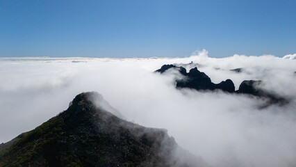 Among the Clouds, a Majestic Mountain Peak Emerges Under a Bright Blue Sky