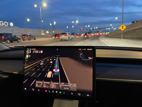 Driving down a highway in traffic at night in a high-tech autonomous Tesla Model 3 vehicle. Full self driving in Chicago, Illinois.