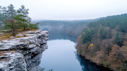 Fototapeta premium Misty morning over a tranquil lake nestled within a valley, viewed from a high rocky outcrop. A serene landscape of autumnal colors