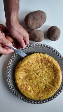 Cutting a Slice of Spanish Tortilla on a White Kitchen Table