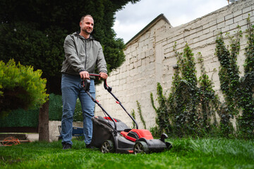Man mowing grass in a lush garden under a serene sky on a pleasant afternoon
