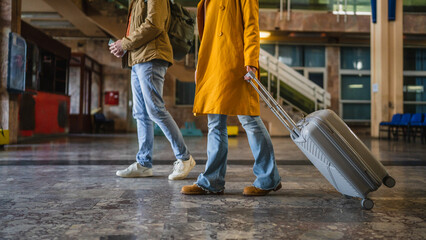 unknown woman and man traveler dragging grey suitcase at train station