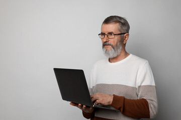 Mature man with laptop on light grey background