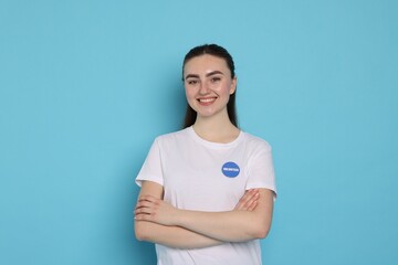 Portrait of smiling volunteer with crossed arms on light blue background