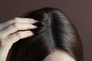 Woman with healthy hair roots on brown background, closeup