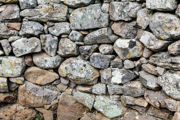 A wall made of rocks with moss growing on it An ancient stone gate building in the nature reserve Nuraghe-Mannu Archaeological Zone on the Island Sardinia in Italy