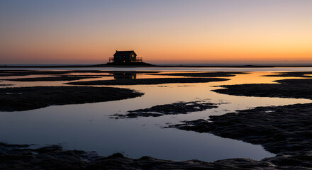 Fototapeta premium Tide Pools Reflecting The Silhouette Of A Distant Beach House At Sunset