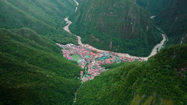 Aerial View of Aguas Calientes Town Nestled in a Lush Green Valley Near Machu Picchu, Peru. Stunning drone footage showing the town of Aguas Calientes, also known as Machu Picchu Pueblo, nestled deep 