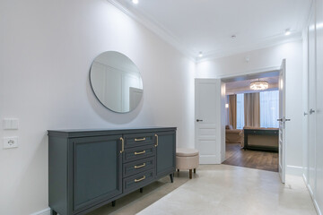 Modern design of the hallway, decorated in white. Elegant furniture, an open double door with a view of the living room.