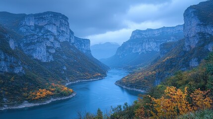 Serene autumnal river carving through majestic, steep canyons under a brooding sky