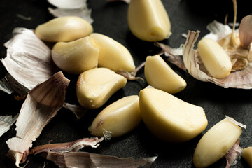 Close up of A rustic scene featuring garlic cloves and peelings scattered, great for illustrating cuisine, food preparation, cooking concepts, and rustic or organic kitchen themes.