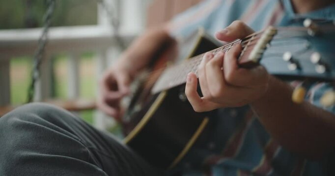 Close up of hands strumming and playing the acoustic guitar 