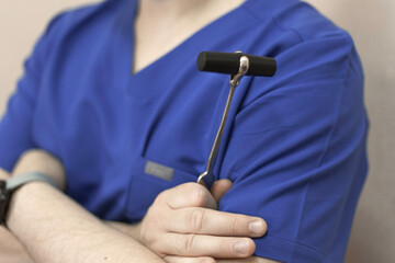 a male doctor holds a reflex nerve tapping instrument in his hand close up