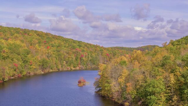 This 4K aerial footage captures the peaceful Canopus Lake in Kent, NY, during the autumn season, with cloudy weather enhancing the scenic view.