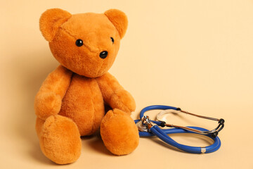 Pediatrics concept. Teddy bear with stethoscope on beige background, space for text