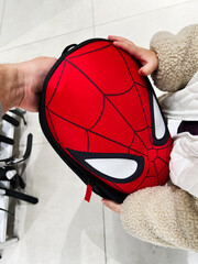 Naklejka premium Person holding a red Spider Man Spider Manthemed backpack with white eyes in a store