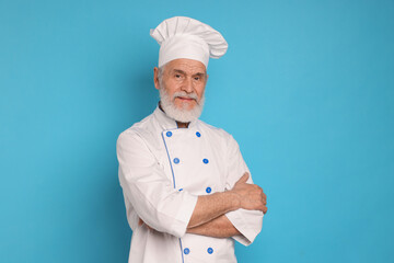 Professional pastry chef with crossed arms on light blue background