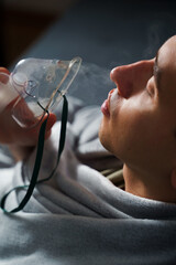Using compressor nebulizer for disease treatment at home. Man inhaling through oxygen mask for...