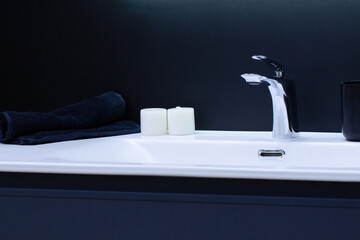white sink with washbasin, two candles and a blue rolled towel
