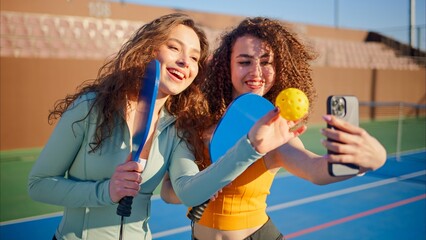 Portrait of young adult curly hair girls posing with pickleball paddles