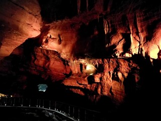 Prometheus cave in Kutaisi, Georgia Illuminated cave interior with reddish-brown textured rock...