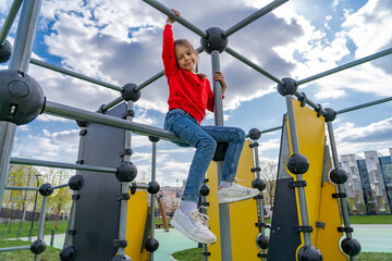 Young girl's joy: Climbing on playground equipment for fun and activity, a carefree childhood adventure