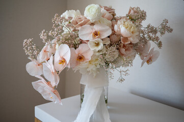 Blush and ivory orchid bouquet with ribbon in glass vase