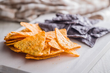 Dark and yellow nachos chips on kitchen table.