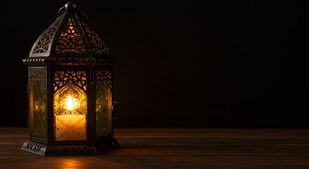 Illuminated Lantern on Dark Wood - A lit candle inside an ornate metal lantern sits on a dark wooden surface against a black background